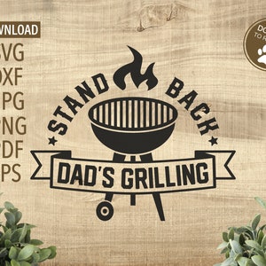 May include: Black and white graphic design with a grill and flames. The text reads "Stand Back Dad's Grilling".
