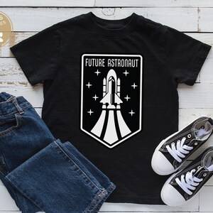 May include: Black t-shirt with a white graphic of a rocket ship and the text "FUTURE ASTRONAUT".