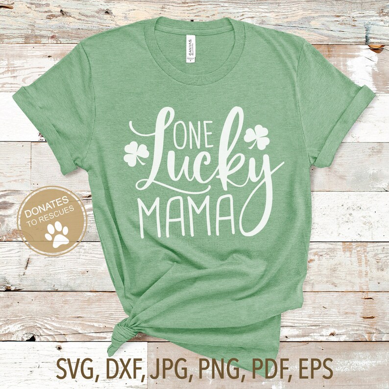 Op de afbeelding: Groen T-shirt met witte tekst die "One Lucky Mama" zegt en een klavertjevier ontwerp.