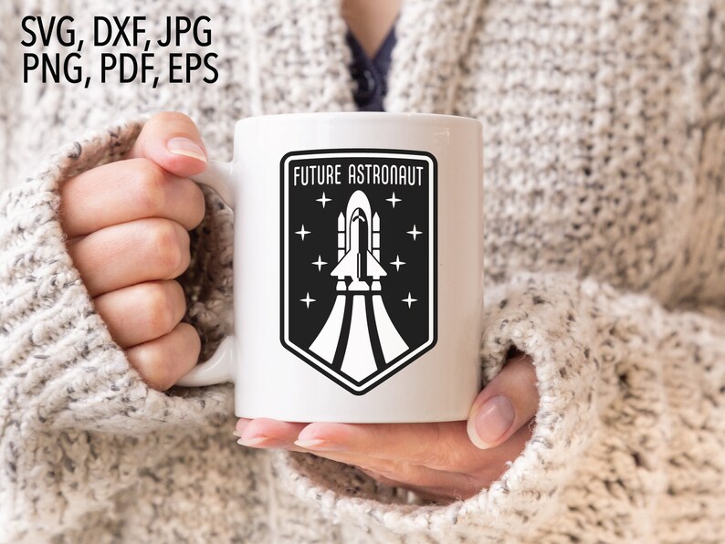 May include: White ceramic mug with a black and white graphic of a rocket ship taking off. The graphic is surrounded by a black shield with the text "FUTURE ASTRONAUT" above the rocket ship and stars around the shield.