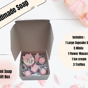 May include: A mini soap gift box containing a large cupcake soap and five mini soaps: a flower macaron, an ice cream, and three truffles. The soaps are pink and white, nestled in silver crinkle paper, inside a brown box. The box is labeled "Handmade Soap".