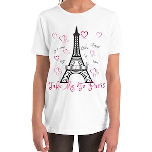 K&ouml;nnte beinhalten: Wei&szlig;es T-Shirt f&uuml;r Jugendliche mit einem schwarzen Motiv des Eiffelturms und rosa Herzen. Der Text "Take Me To Paris" ist in rosa Kursivschrift unter dem Turm geschrieben. Das Motiv enth&auml;lt auch franz&ouml;sische S&auml;tze wie "Je t'aime" und "Bisous".