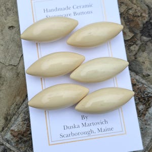 Puede incluir: Seis botones de cerámica de color crema en forma ovalada. Los botones están hechos a mano por Duska Martovich en Scarborough, Maine.