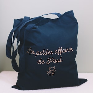 May include: A dark blue tote bag with the text "Les petites affaires de Paul" and a small fox illustration in the bottom right corner.