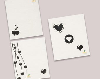 May include: Three white notepads with black heart designs. The notepads have the text "Aspen Creations" printed on them.
