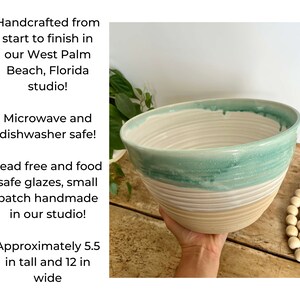 May include: A large, handmade ceramic bowl with a light green glaze and white stripes. The bowl is 5.5 inches tall and 12 inches wide. It is microwave and dishwasher safe.