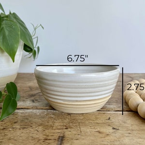 K&ouml;nnte beinhalten: Wei&szlig;e Keramiksch&uuml;ssel mit einem hellbraunen Rand. Die Sch&uuml;ssel hat ein geriffeltes Design und misst 17,1 cm im Durchmesser und 7 cm in der H&ouml;he.