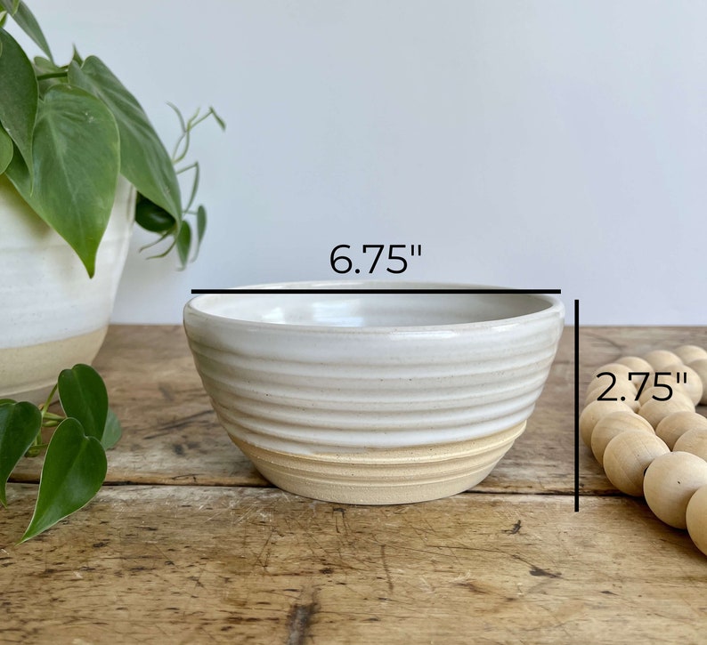 K&ouml;nnte beinhalten: Wei&szlig;e Keramiksch&uuml;ssel mit einem hellbraunen Rand. Die Sch&uuml;ssel hat ein geriffeltes Design und misst 17,1 cm im Durchmesser und 7 cm in der H&ouml;he.