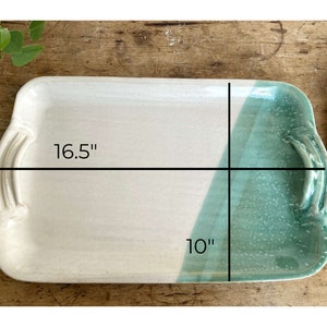 May include: A rectangular ceramic serving tray with a white glaze and a green glaze on one side. The tray measures 16.5 inches by 10 inches.