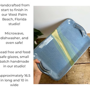 May include: A blue ceramic serving tray with yellow and green glaze accents. The tray has two handles and measures approximately 16.5 inches long and 10 inches wide. It is handcrafted in West Palm Beach, Florida and is microwave, dishwasher, and oven safe.