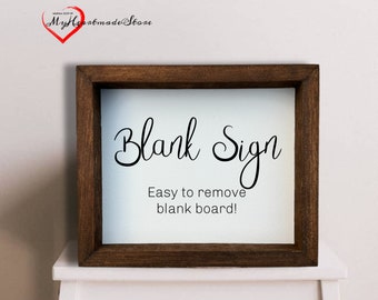 Puede incluir: Un marco de madera marrón con fondo blanco y el texto "Blank Sign" en fuente cursiva negra. Debajo del texto está la frase "Easy to remove blank board!" en texto negro.