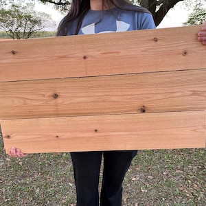 May include: A natural wood sign with four horizontal planks. The wood is a light brown color with a smooth finish.