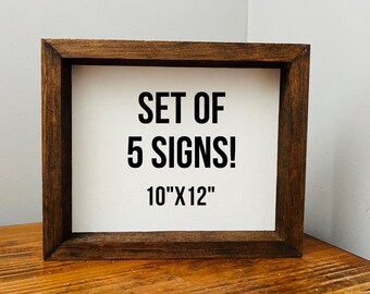 May include: A set of 5 signs in a brown wooden frame. The signs are 10 inches by 12 inches and have the text "SET OF 5 SIGNS!" printed on them.