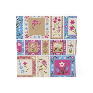 Könnte beinhalten: Ein farbenfrohes Muster mit verschiedenen Blumen in blauen, rosa und weißen Rahmen. Das Design erinnert an eine Steppdecke oder ein Patchwork.