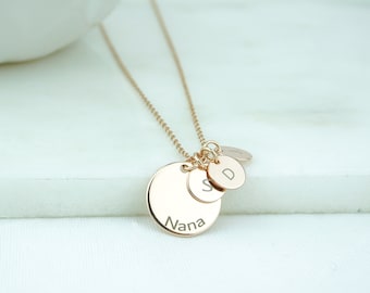 May include: A gold necklace with three round charms. The largest charm says "Nana" and the two smaller charms have the letters "S" and "D" engraved on them.