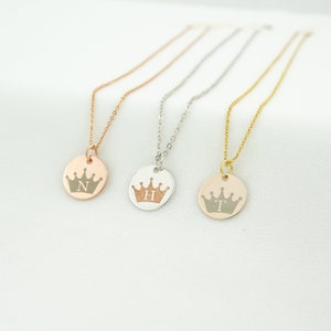 May include: Three gold necklaces with round pendants featuring a crown design and a single letter, N, H, and T.