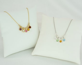 May include: Two necklaces with small colorful gemstone charms. The necklace on the left has gold chain and red, pink, white, and yellow gemstones. The necklace on the right has a silver chain and green, yellow, and blue gemstones.