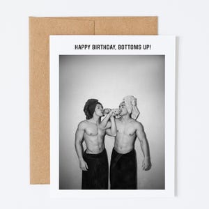 May include: A white ceramic mug with a black handle and the text "But First, Coffee" in a bold, black font. The mug is sitting on a wooden surface. The mug is approximately 4 inches tall.