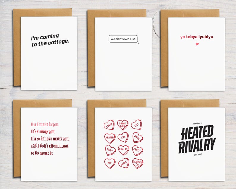Puede incluir: Seis tarjetas de felicitaci&oacute;n blancas con sobres marrones, cada una con texto o gr&aacute;ficos &uacute;nicos. Las frases incluyen I'm coming to the cottage, We didn't even kiss, ya tebya lyublyu con un coraz&oacute;n, texto estilizado, caramelos de coraz&oacute;n rojos con texto y HEATED RIVALRY.