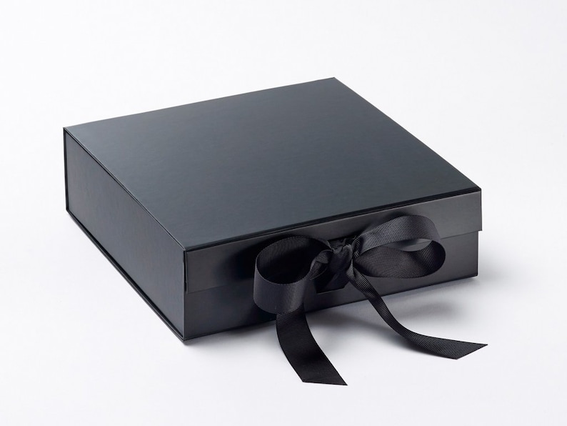 May include: A black gift box with a matching black ribbon tied in a bow. The box is rectangular with a glossy finish. The ribbon is made of a satin-like material. The box is closed and ready for gifting.