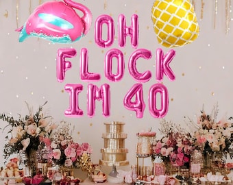 May include: Pink and gold foil balloons spelling "Oh Flock I'm 40" with a pink flamingo and a pineapple balloon. The balloons are decorated on a table with pink and gold decorations.