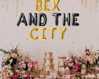 May include: A pink and gold party table setting with black and gold balloons spelling out "Bex and the City".