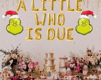 May include: A baby shower party decoration with gold foil balloons spelling "A Little Who Is Due" and two green Grinch characters with red Santa hats on either side.