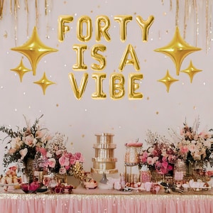 May include: A pink and gold birthday party table setting with a banner that reads "Forty is a Vibe". The table is decorated with flowers, candles, and a tiered cake stand.