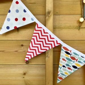May include: A colourful bunting with red, white and blue flags. The flags have different patterns, including polka dots, zigzags and fish.