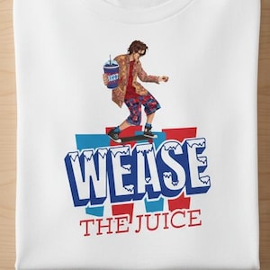 May include: White crew neck t-shirt featuring a graphic of a person skateboarding on a blue and red platform. The text "WEASE THE JUICE" is below the skater. The skater is wearing a patterned jacket and shorts.