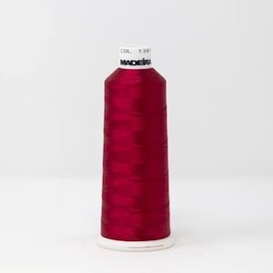 May include: A spool of Madeira thread in a rich, deep red hue. The thread is neatly wound on a white spool, with the brand name and colour details visible. The thread is a solid, vibrant colour, ideal for a range of sewing and embroidery tasks.
