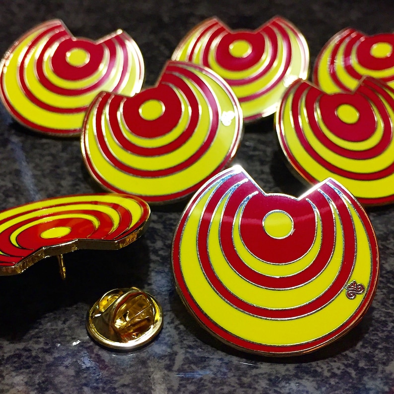 May include: Six yellow and red enamel pins with a concentric circle design. The pins are in the shape of a crescent moon.