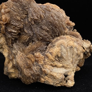 May include: A large, rough, brown and white rock with a cluster of brown, needle-like crystals.
