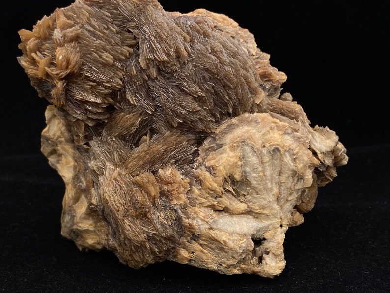 May include: A large, rough, brown and white rock with a cluster of brown, needle-like crystals.
