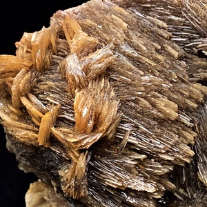 May include: A cluster of brown, shimmery, and translucent crystals with a rough, textured surface.