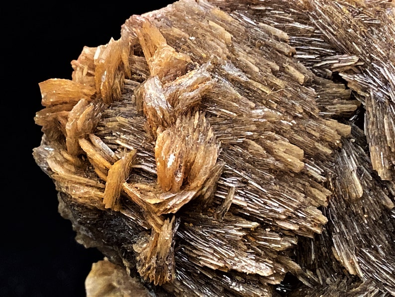 May include: A cluster of brown, shimmery, and translucent crystals with a rough, textured surface.