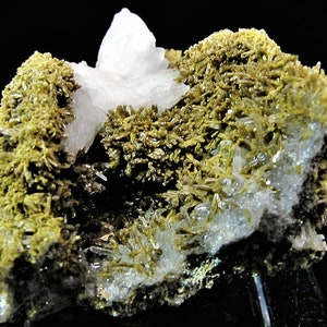 May include: A cluster of clear quartz crystals with green actinolite crystals. The quartz crystals have a glassy lustre. The actinolite crystals are green and have a fibrous texture.