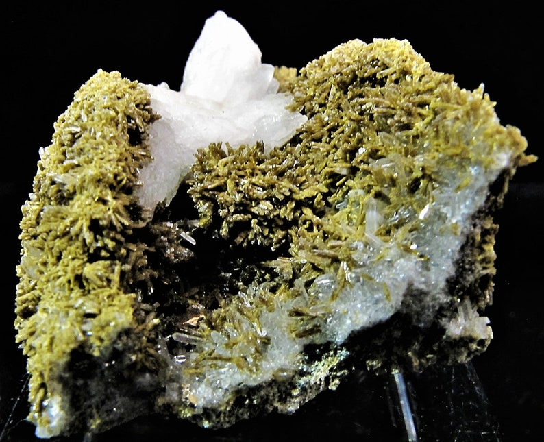 May include: A cluster of clear quartz crystals with green actinolite crystals. The quartz crystals have a glassy lustre. The actinolite crystals are green and have a fibrous texture.