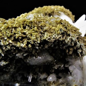 May include: A cluster of white and light green crystals. The crystals are arranged in a random pattern and have a rough, textured surface.