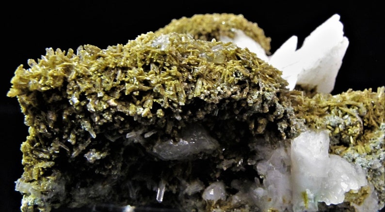 May include: A cluster of white and light green crystals. The crystals are arranged in a random pattern and have a rough, textured surface.