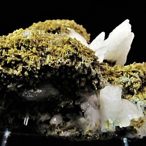 May include: A cluster of white, translucent crystals with a rough, brown, fibrous matrix. The crystals are sharp and well-defined, with a slight pink hue.