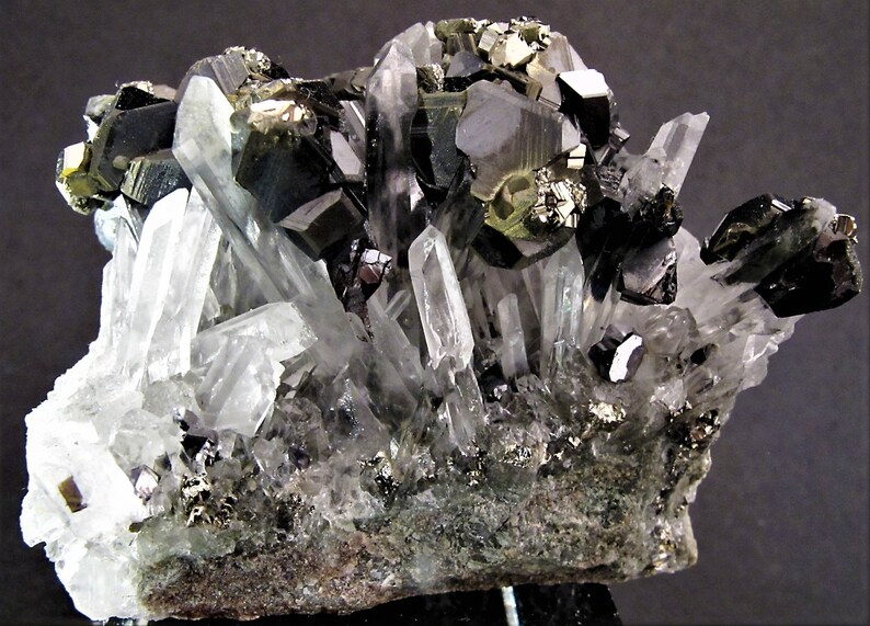 May include: A cluster of black and silver crystals with a clear quartz matrix. The crystals are arranged in a natural, organic pattern, creating a visually appealing and unique specimen.
