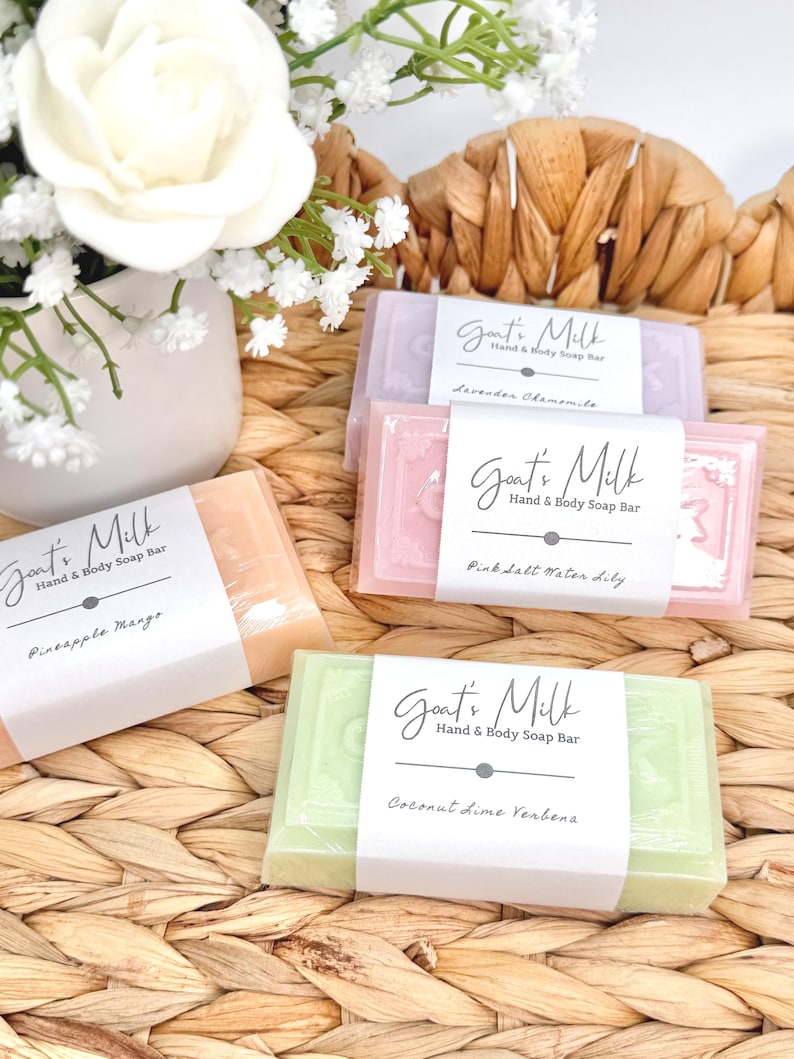 Puede incluir: Cuatro pastillas de jab&oacute;n rectangulares de leche de cabra para manos y cuerpo en colores lavanda, rosa, naranja y verde claro. Cada pastilla tiene una etiqueta de papel blanco con el texto Goat's Milk Hand & Body Soap Bar y los nombres de aroma Lavender Chamomile, Pink Salt Water Lily, Pineapple Mango y Coconut Lime Verbena.