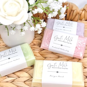 Puede incluir: Cuatro pastillas de jab&oacute;n de leche de cabra para manos y cuerpo en colores verde claro, amarillo, rosa y lavanda. Cada pastilla tiene una etiqueta de papel blanco con el texto Goat's Milk Hand & Body Soap Bar y los nombres de los aromas Coconut Lime Verbena, Georgia Peach, Pink Salt Water Lily y Lavender Chamomile.