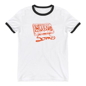Könnte beinhalten: Weißes T-Shirt mit schwarzem Ringel, mit einem Vintage-Kassettenband mit dem Text "Everybody Wants Some" in Orange.