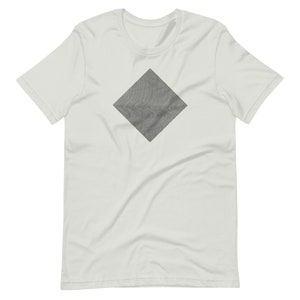 Puede incluir: Una camiseta blanca con un diseño gris en forma de diamante. El diseño tiene un patrón texturizado y ondulado.