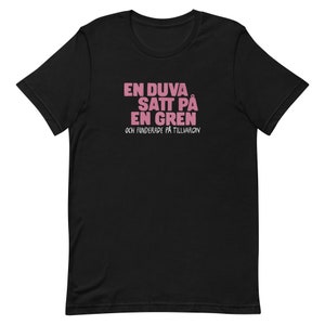 May include: Black t-shirt with pink text that reads "En duva satt på en gren och funderade på tillvaron".