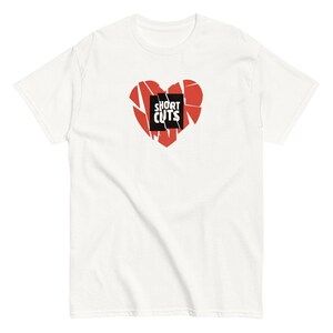 May include: White t-shirt featuring a red broken heart graphic with the text "SHORT CUTS" in a black box.