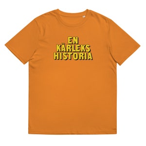 May include: A bright orange t-shirt with the text "EN KÄRLEKS HISTORIA" in yellow outlined in black.