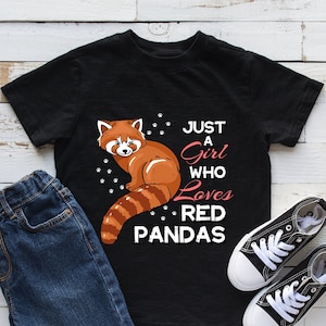 May include: Black t-shirt with a red panda graphic and the text "Just a Girl Who Loves Red Pandas." The shirt is paired with blue jeans and black canvas sneakers.